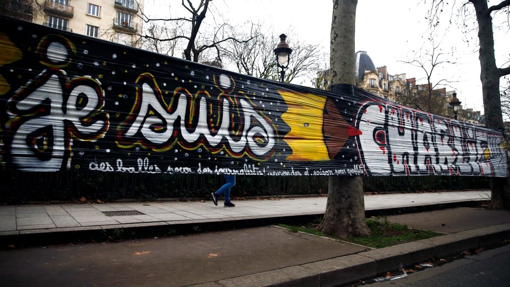A woman walks behind a large banner stating 'Je suis Charlie' that is hung between trees next the 'Charlie Hebdo' offices in Paris, France, on Jan. 12, 2015. (Photo by Etienne Laurent/EPA)
