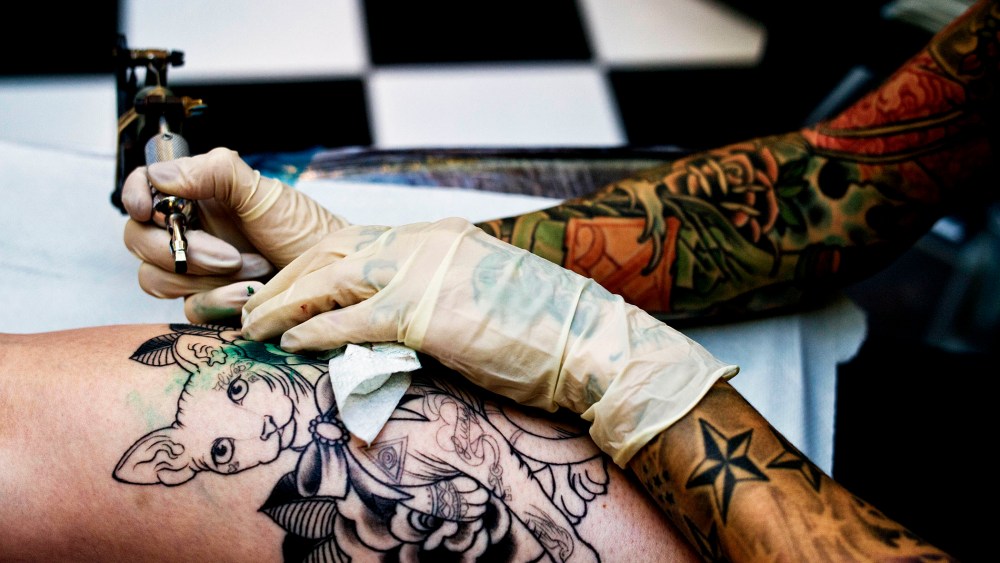 A tattoo artist works on a client at the The Family Business Tattoo parlor.