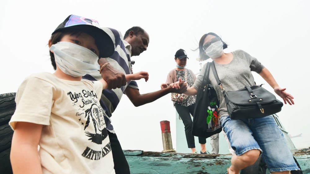 Tourists with masks get off a boat in Port Klang, Malaysia, March 14, 2014.