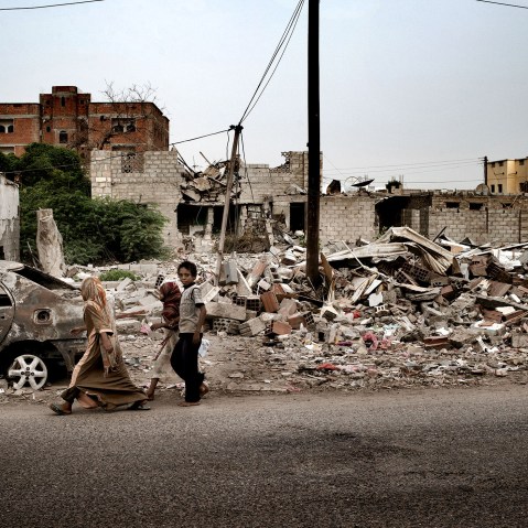 Civilians pass a house destroyed by a US drone strike in the town of Jaar, in the Abyan province of Yemen.