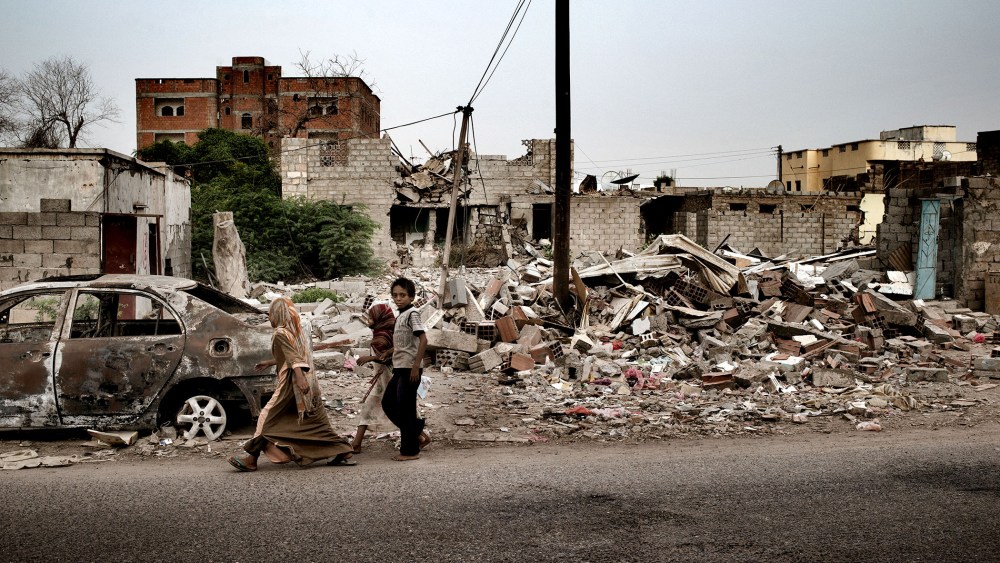 Civilians pass a house destroyed by a US drone strike in the town of Jaar, in the Abyan province of Yemen.