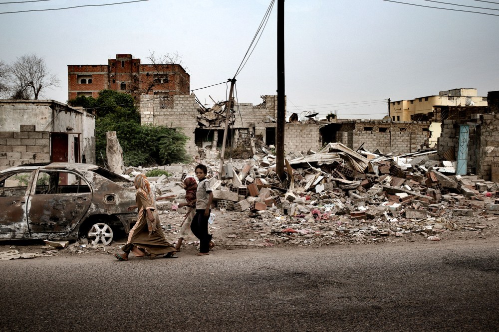 Civilians pass a house destroyed by a US drone strike in the town of Jaar, in the Abyan province of Yemen.