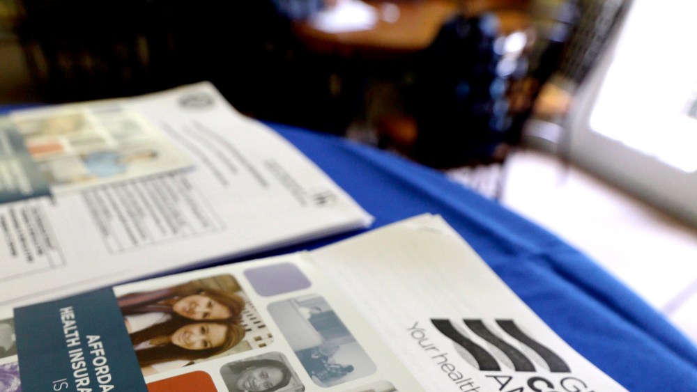 In this March 10, 2014 photo, with Health care information in the foreground, participants learn more about their health care options.
