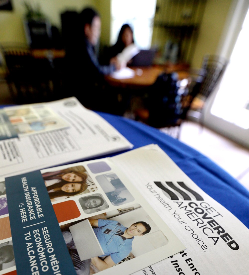 In this March 10, 2014 photo, with Health care information in the foreground, participants learn more about their health care options.