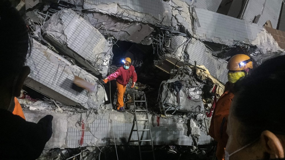 A rescue worker (C) discards an object as he searches through rubble for belongings for relatives from the remains of a building which collapsed. (Photo by Anthony Wallace/AFP/Getty)
