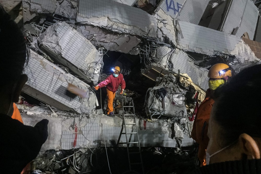 A rescue worker (C) discards an object as he searches through rubble for belongings for relatives from the remains of a building which collapsed. (Photo by Anthony Wallace/AFP/Getty)