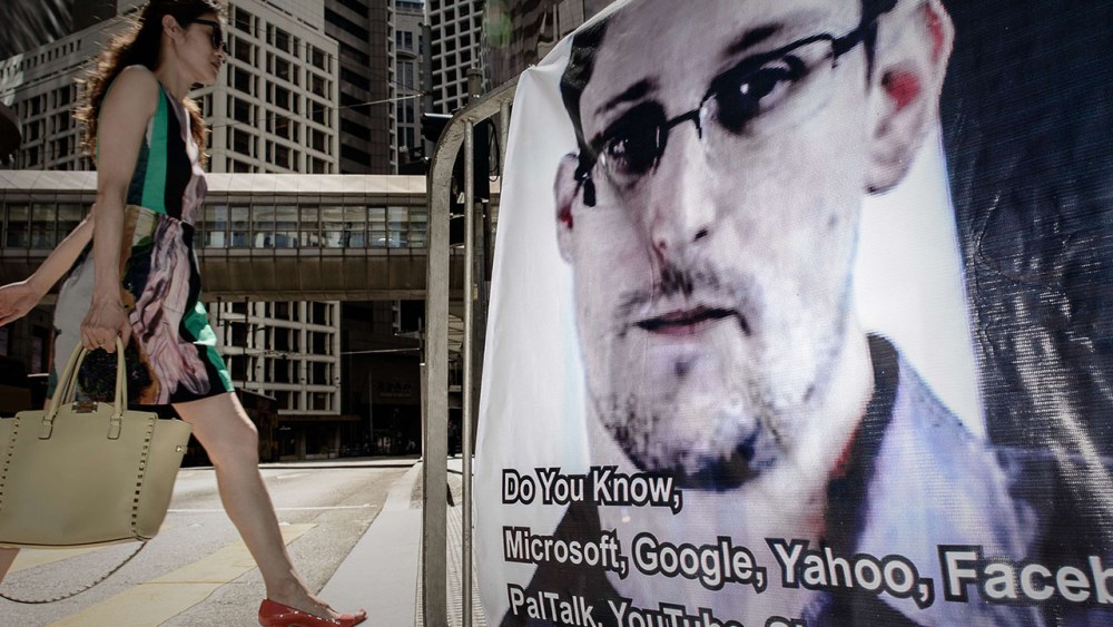 This file picture taken on June 18, 2013 shows a woman walking past a banner displayed in support of former US spy Edward Snowden in Hong Kong.  (Photo by Philippe Lopez/AFP/Getty Images)