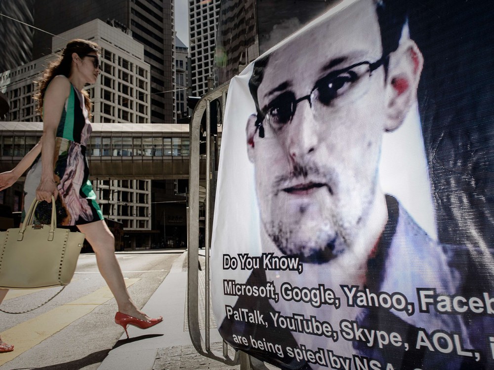 This file picture taken on June 18, 2013 shows a woman walking past a banner displayed in support of former US spy Edward Snowden in Hong Kong. (Photo by Philippe Lopez/AFP/Getty Images)