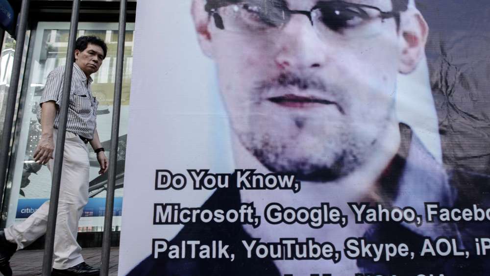 This picture taken on June 18, 2013 shows a man walking past a banner displayed in support of former National Security Agency contractor Edward Snowden in Hong Kong.  (AFP PHOTO / Philippe Lopez)