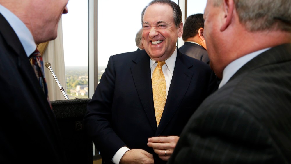 Former Arkansas Gov. Mike Huckabee laughs as he is greeted after a meeting of the Political Animals Club in Little Rock, Ark., Oct. 25, 2013.