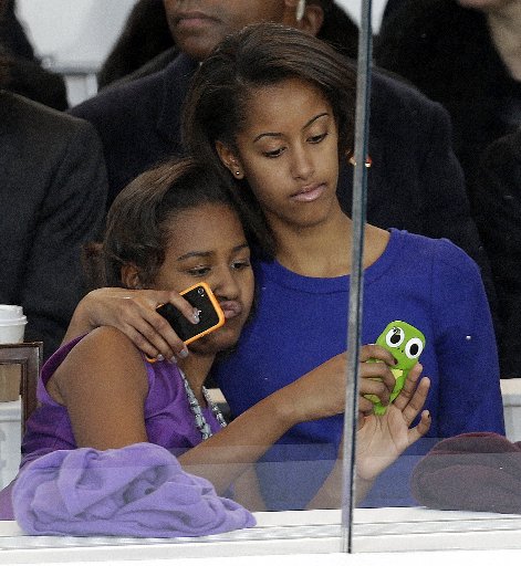 Malia and Sasha Obama look on from the presidential box. (Photo by AP/Gerald Herbert)