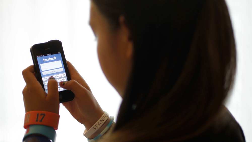 An unidentified 11-year-old girl logs into Facebook on her iPhone at her home in Palo Alto, Calif. in 2012. (AP Photo/Paul Sakuma)