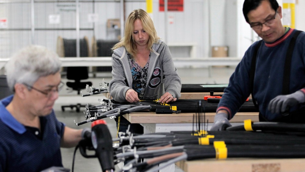 In this Nov. 2, 2012 photo, Jenifer Zeleny, center, does a quality-control inspection, as workers manufacture cables used in wind turbines, inside the production area at the Walker Components factory, in Denver. One-third of the workers at the factory...