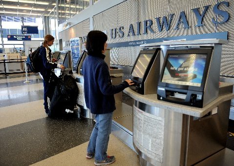 Customers check in at a US Airways ticket counter at Chicago's O'Hare airport on August 13, 2013. The US Justice Department and several states sued Tuesday to block the $11 billion merger between American Airlines and US Airways, saying it would reduce...