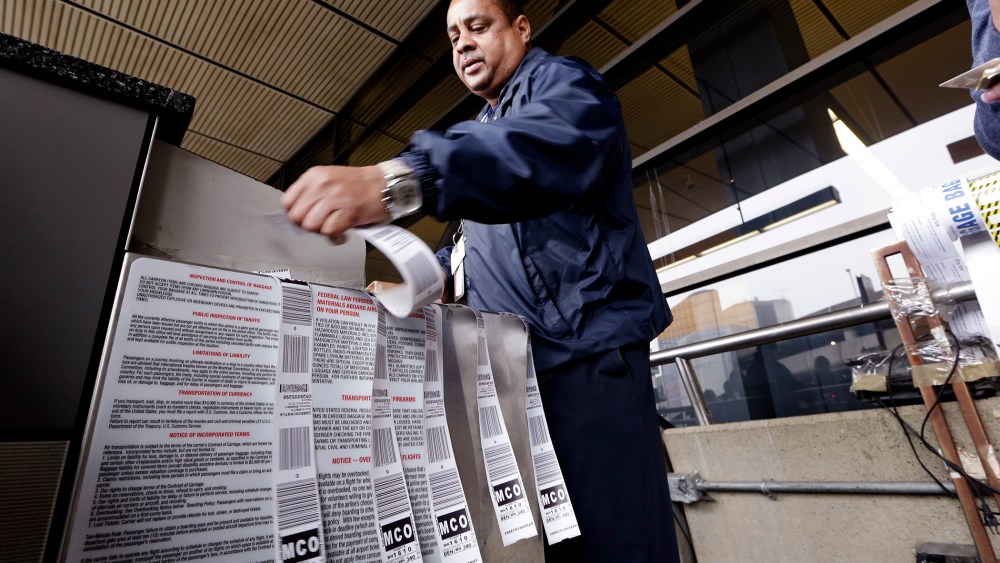 veteran skycap Fred Harris prepares multiple baggage tags for a traveler at Seattle-Tacoma International Airport in SeaTac, Wash.