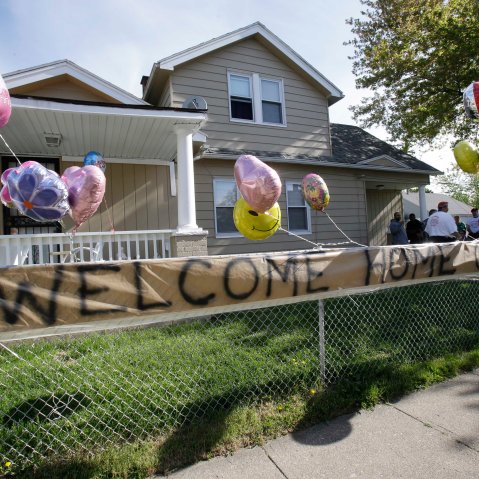 A "Welcome Home Gina " sign hangs on a fence outside the home of Gina DeJesus  Tuesday, May 7, 2013, in Cleveland.  DeJesus, Amanda Berry and Michelle Knight, who went missing separately about a decade ago, were found in a home just south of downtown...