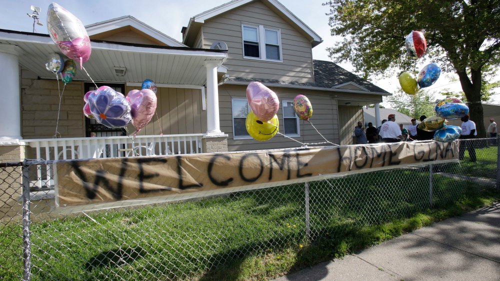 A "Welcome Home Gina " sign hangs on a fence outside the home of Gina DeJesus  Tuesday, May 7, 2013, in Cleveland.  DeJesus, Amanda Berry and Michelle Knight, who went missing separately about a decade ago, were found in a home just south of downtown...