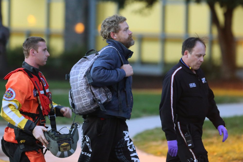 Louis Jordan, center, walks from the Coast Guard helicopter to the Sentara Norfolk General Hospital in Norfolk, Va., after being found off the North Carolina coast, on April 2, 2015. (Photo by Steve Earley/The Virginian-Pilot/AP)