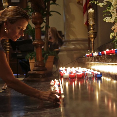 A woman places a candle on the altar during a prayer service for the victims of The Grand 16 theater shooting at the Cathedral of St. John the Evangelist, in Lafayette, La., July 26, 2015. (Photo by Gerald Herbert/AP)