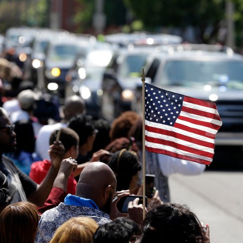 A mourner holds an American flag as the funeral procession for Muhammad Ali makes its way down Muhammad Ali Boulevard in Louisville, Ky. on June 10, 2016. (Photo by Michael Conroy/AP)