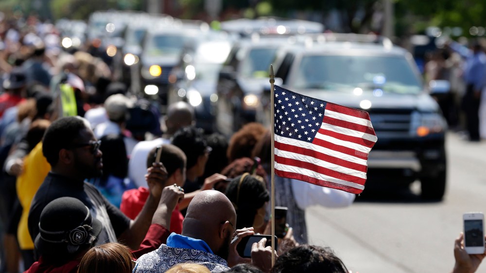 A mourner holds an American flag as the funeral procession for Muhammad Ali makes its way down Muhammad Ali Boulevard in Louisville, Ky. on June 10, 2016. (Photo by Michael Conroy/AP)