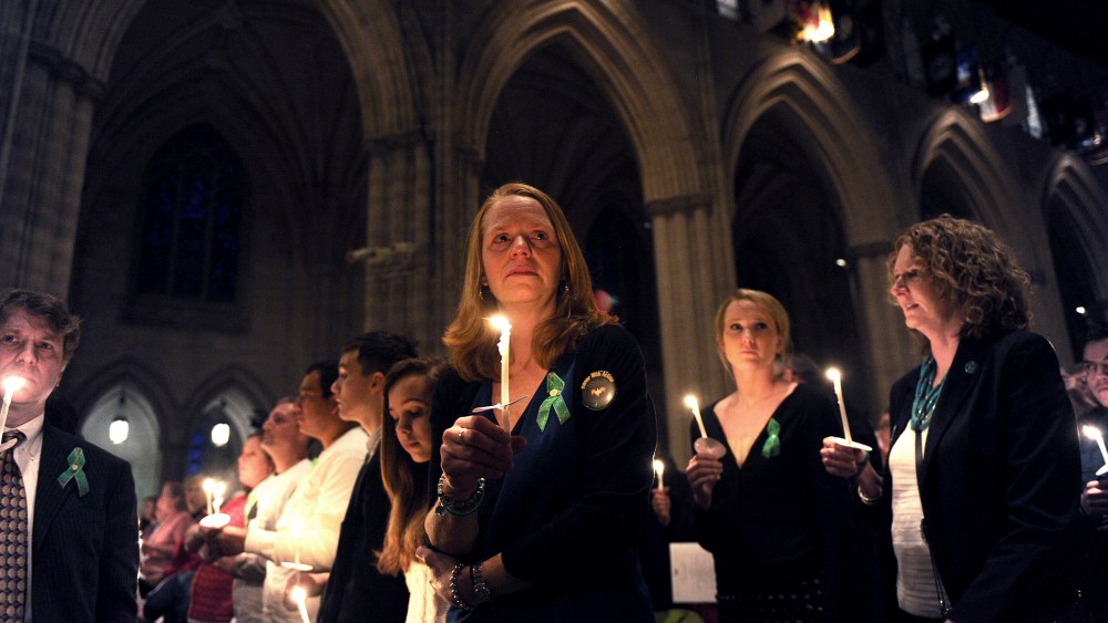 Miranda Pacchiana, center, of Newtown, Conn., holds a candle at the conclusion of a vigil to remember those who lost their lives because of gun violence on Thursday, Dec. 12, 2013 at the National Cathedral in Washington, D.C.