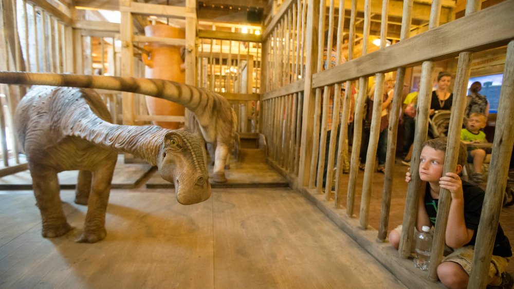 A visitor looks into a cage containing a model dinosaur inside a replica Noah's Ark at the Ark Encounter theme park during a media preview day, Tuesday, July 5, 2016, in Williamstown, Ky.
