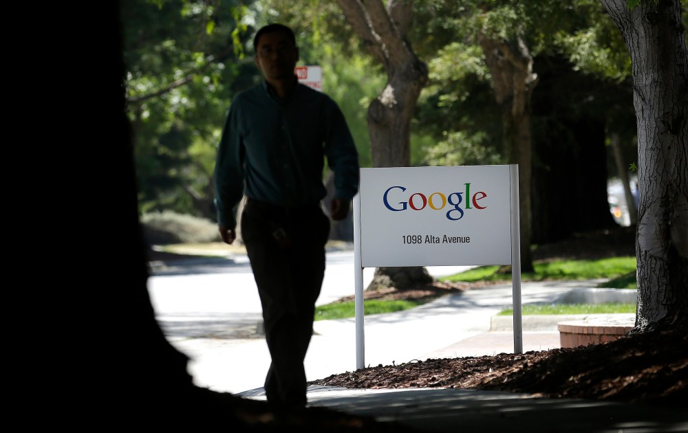 A man walks past a Google sign in Mountain View, Calif., Friday, June 7, 2013. Google CEO Larry Page is denying reports linking the Internet search company to a secret government program that has provided the National Security Agency access to email...