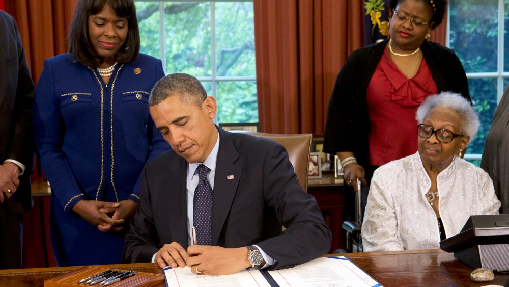 President Barack Obama signs a bill designating the Congressional Gold Medal commemorating the lives of the four young girls killed in the 16th Street Baptist Church Bombing of 1963, Friday, May 24, 2013, in the Oval Office of the White House. Standing...