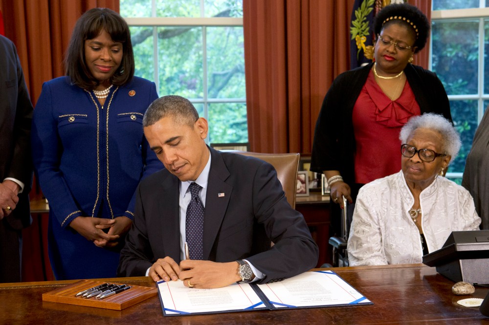 President Barack Obama signs a bill designating the Congressional Gold Medal commemorating the lives of the four young girls killed in the 16th Street Baptist Church Bombing of 1963, Friday, May 24, 2013, in the Oval Office of the White House. Standing...