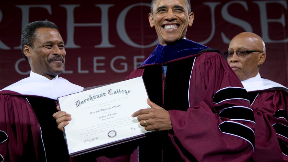 Morehouse College President John Silvanus Wilson Jr. stands left and Robert Davidson, Chair of the Board of Trustees, right, as President Barack Obama holds his honorary a doctorate of laws degree during the Morehouse College 129th Commencement...