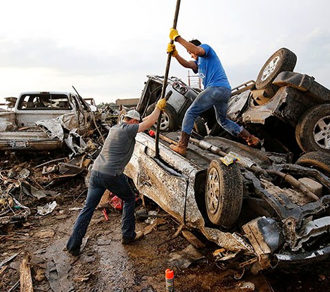 Two men attempt  to pry open a door on this car to check for victims in a business parking lot west of I-35 south of 4th Street in Moore, on May 20, 2013. (AP Photo/The Oklahoman, Jim Beckel)