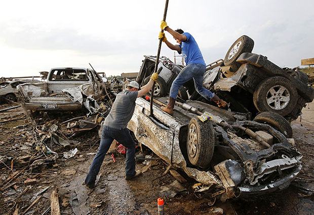 Two men attempt  to pry open a door on this car to check for victims in a business parking lot west of I-35 south of 4th Street in Moore, on May 20, 2013. (AP Photo/The Oklahoman, Jim Beckel)