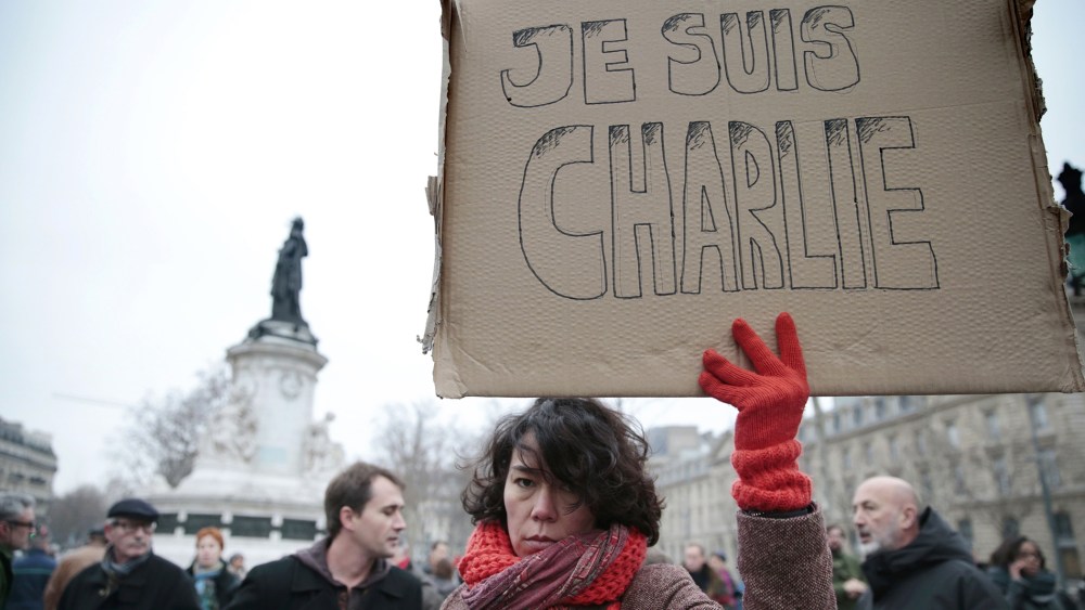A woman holds up a placard that reads in French, "I am Charlie" as she and others gather at the Place de la Republique in the French capital Paris, on Jan. 7, 2015, following an attack by unknown gunmen on the offices of the satirical weekly, Charlie Hebd