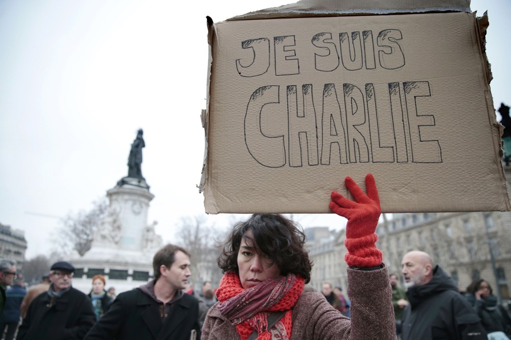 A woman holds up a placard that reads in French, "I am Charlie" as she and others gather at the Place de la Republique in the French capital Paris, on Jan. 7, 2015, following an attack by unknown gunmen on the offices of the satirical weekly, Charlie Hebd