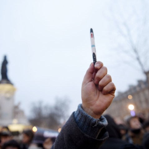 A man raises a pen during a rally in support of the victims of today's terrorist attack on French satyrical newspaper Charlie Hebdo at the Place de la Republique in Paris, on Jan. 7, 2015.