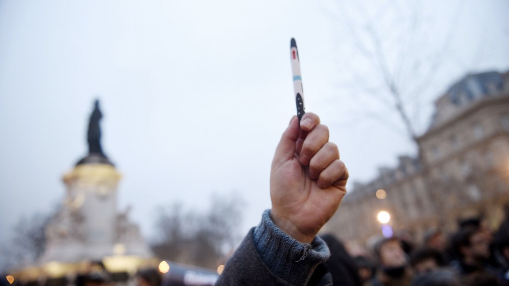 A man raises a pen during a rally in support of the victims of today's terrorist attack on French satyrical newspaper Charlie Hebdo at the Place de la Republique in Paris, on Jan. 7, 2015.