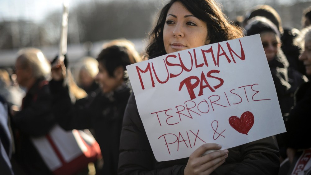 A woman hold a placard reading in French "Muslim not terrorists, peace and love" during a gathering in the center of Geneva on Jan. 8, 2015 to pay tribute to the twelve people killed the day before in an attack by two armed gunmen on the offices of Fre