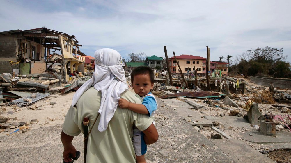 A man walks home with his son Monday Nov. 11, 2013, following Friday's devastating typhoon that lashed Hernani township, in eastern Samar province, in the central Philippines.