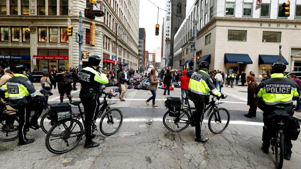 Pittsburgh police on bicycles block traffic from demonstrators protesting the deaths of two unarmed black men at the hands of white police officers in New York City and Ferguson, Mo. as they lay in the street during march through Pittsburgh on Dec. 4, 201