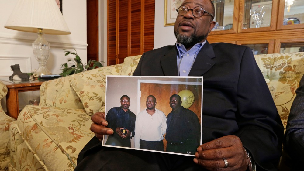Anthony Scott holds a photo of himself, center, and his brothers Walter Scott, left, and Rodney Scott, right, as he talks about his brother at his home near North Charleston, S.C., on April 8, 2015.