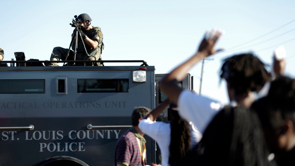 A member of the St. Louis County Police Department points his weapon in the direction of a group of protesters in Ferguson, Mo. on Wednesday, Aug. 13, 2014.