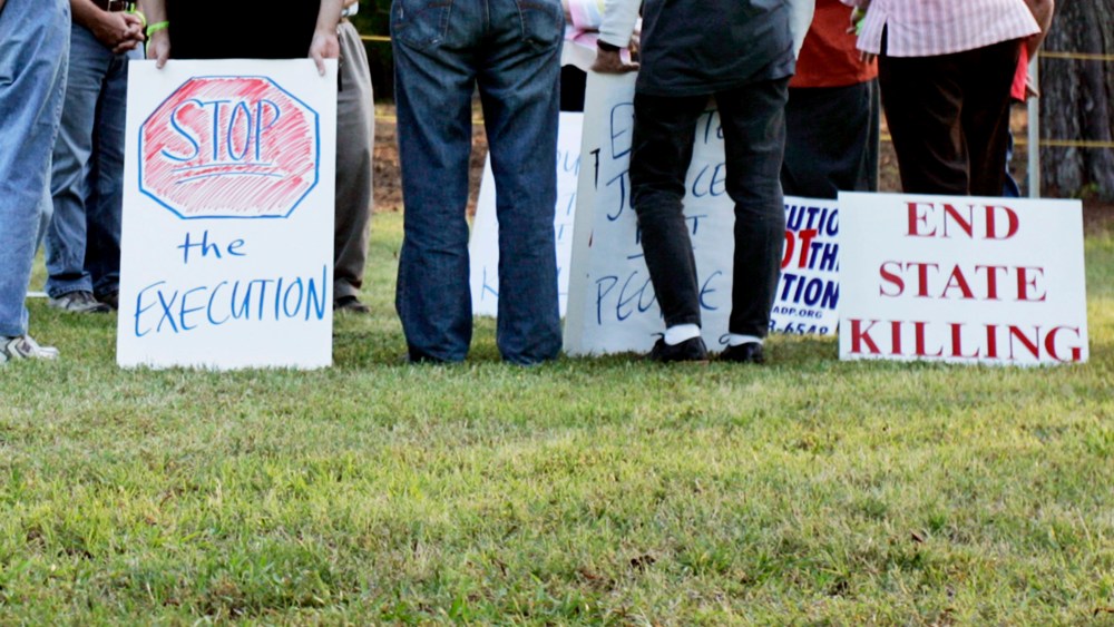 Protestors opposed to the death penalty hold signs and sing songs during a vigil at the Georgia Diagnostic and Classification Prison in Jackson, Georgia.