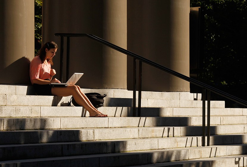 A student uses her laptop computer on the steps to Memorial Church at Harvard University in Cambridge, Mass.