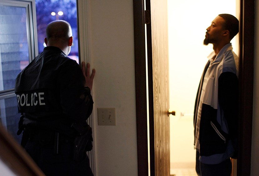 Suspect Gerald Ware (R) stands handcuffed in the doorway of his home as police conduct a raid in search of illegal drugs during the execution of a search warrant for marijuana in Kalamazoo, Michigan, on November 12, 2009 file picture.  (Photo by John...