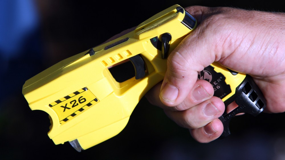 A police officer poses with a taser. (Photo by Sebastien Nogier/Reuters)