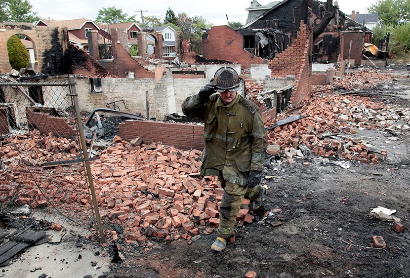 A Detroit fire fighter looks through the smoldering back yards of burned homes and garages on East Robinwood in Detroit, Michigan September 8, 2010.  Detroit's bankruptcy will likely fall hardest on  public sector employees.  (Photo by Rebecca Cook...