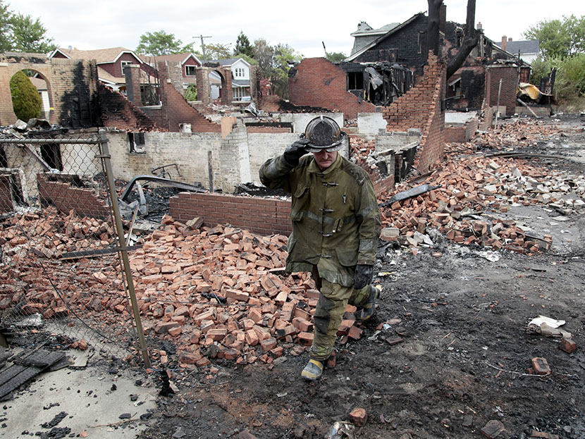 A Detroit fire fighter looks through the smoldering back yards of burned homes and garages on East Robinwood in Detroit, Michigan September 8, 2010.  Detroit's bankruptcy will likely fall hardest on  public sector employees.  (Photo by Rebecca Cook...