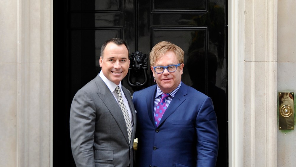 British entertainer Elton John poses for photographs with his partner David Furnish outside 10 Downing Street before a meeting with Prime Minister David Cameron in London