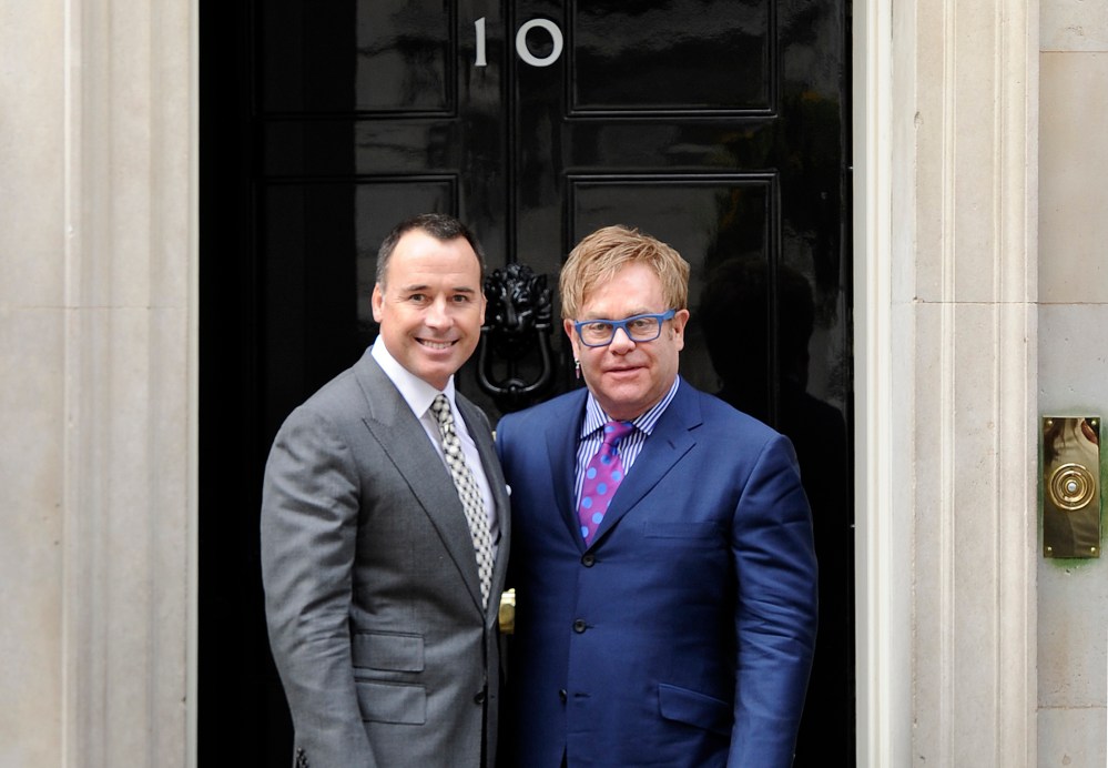 British entertainer Elton John poses for photographs with his partner David Furnish outside 10 Downing Street before a meeting with Prime Minister David Cameron in London